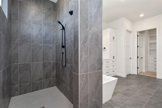 bathroom with baseboards, tiled shower, and a walk in closet