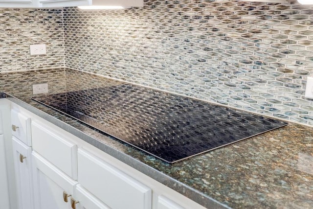 room details with white cabinets, black electric stovetop, and backsplash