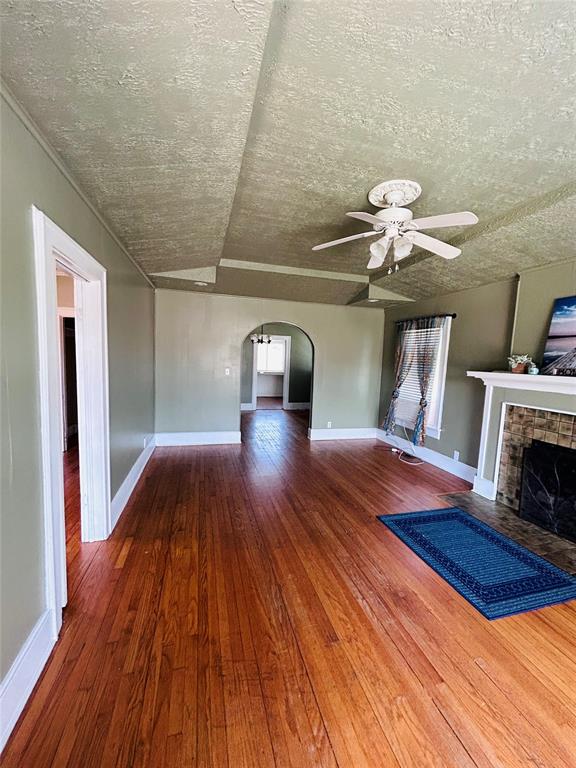 unfurnished living room with hardwood / wood-style flooring, ceiling fan, and a textured ceiling