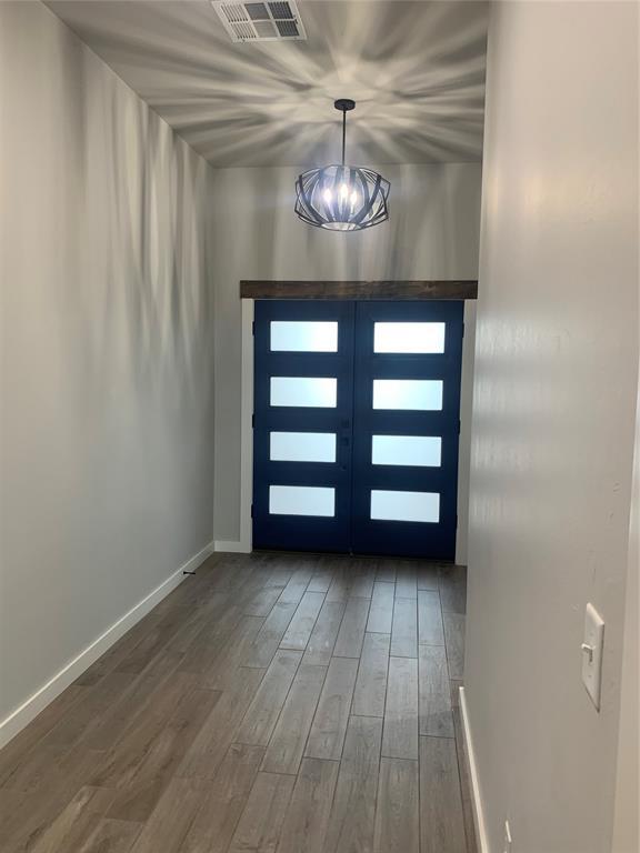 foyer featuring hardwood / wood-style floors, french doors, and an inviting chandelier