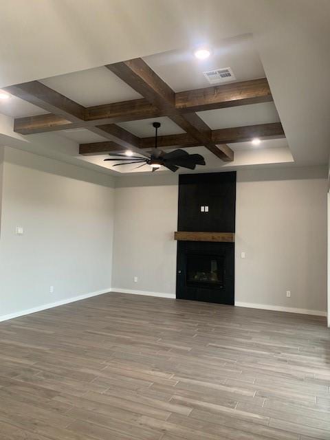 unfurnished living room featuring ceiling fan, light hardwood / wood-style floors, a fireplace, and coffered ceiling