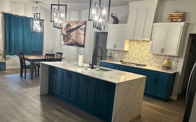 kitchen featuring sink, blue cabinetry, white cabinets, hardwood / wood-style floors, and hanging light fixtures