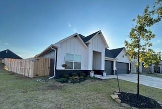 modern farmhouse style home with a front yard and a garage