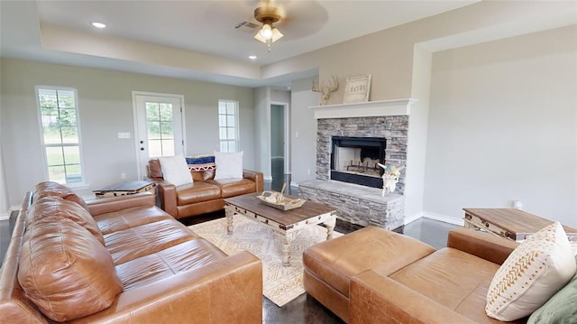 living room featuring dark hardwood / wood-style floors, ceiling fan, and a stone fireplace