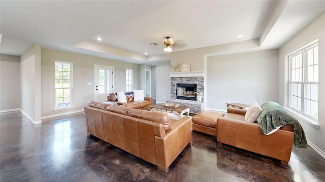 living room featuring a fireplace, a raised ceiling, and ceiling fan