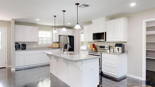 kitchen with a kitchen island with sink, sink, light stone counters, white cabinetry, and stainless steel appliances