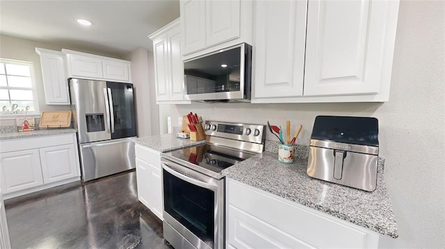 kitchen featuring white cabinets, stainless steel appliances, and light stone counters