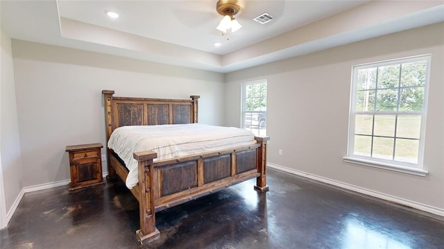 bedroom with a raised ceiling, multiple windows, and ceiling fan