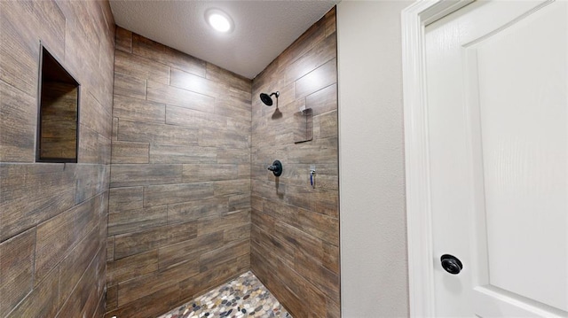 bathroom with a tile shower and a textured ceiling