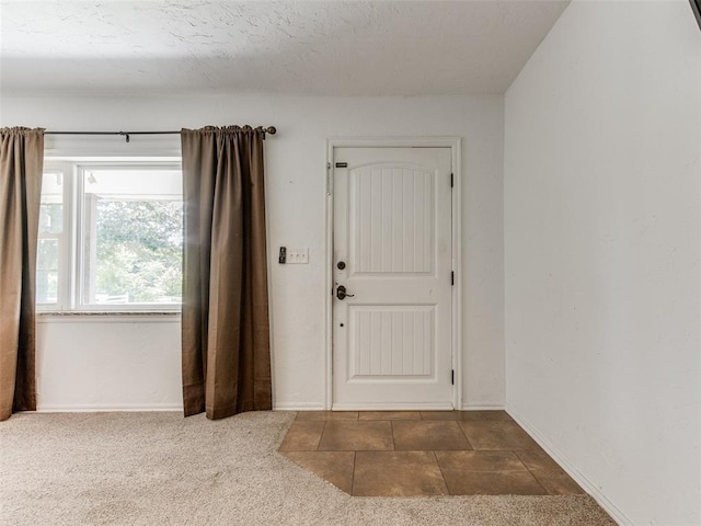 carpeted foyer featuring a textured ceiling