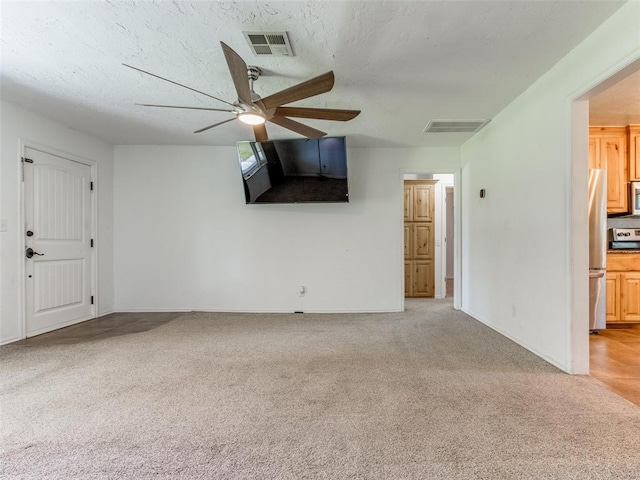 unfurnished living room featuring light carpet, a textured ceiling, and ceiling fan