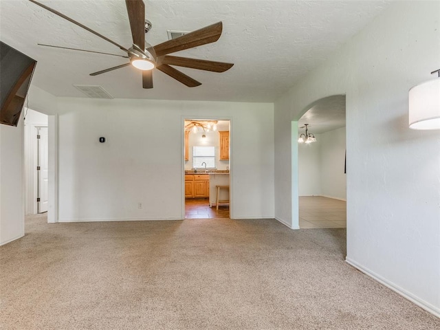 empty room with ceiling fan with notable chandelier, light colored carpet, and sink