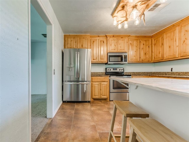 kitchen featuring a notable chandelier, light colored carpet, light brown cabinetry, and appliances with stainless steel finishes