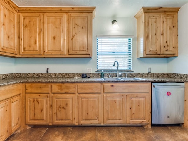 kitchen featuring stainless steel dishwasher, dark tile patterned floors, dark stone counters, and sink