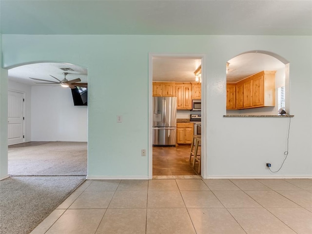 kitchen with ceiling fan, light brown cabinets, light colored carpet, and appliances with stainless steel finishes