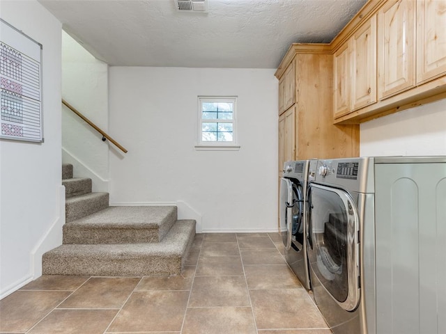 laundry room with tile patterned floors, cabinets, a textured ceiling, and washing machine and dryer