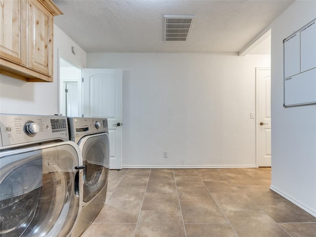 laundry room with washer and clothes dryer, light tile patterned floors, cabinets, and a textured ceiling