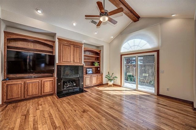 unfurnished living room featuring ceiling fan, beam ceiling, a fireplace, and light hardwood / wood-style flooring