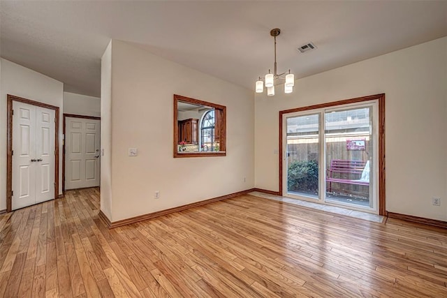 unfurnished room featuring a chandelier and light wood-type flooring