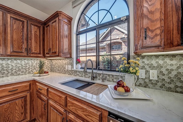 kitchen featuring light stone countertops, tasteful backsplash, and sink