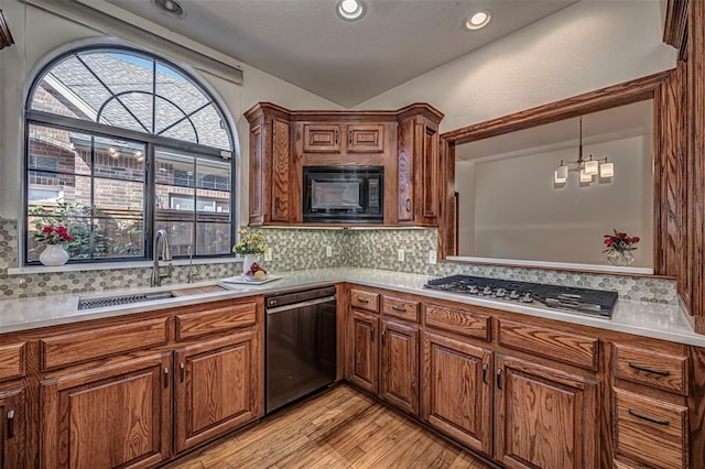 kitchen featuring decorative backsplash, stainless steel appliances, sink, an inviting chandelier, and light hardwood / wood-style floors