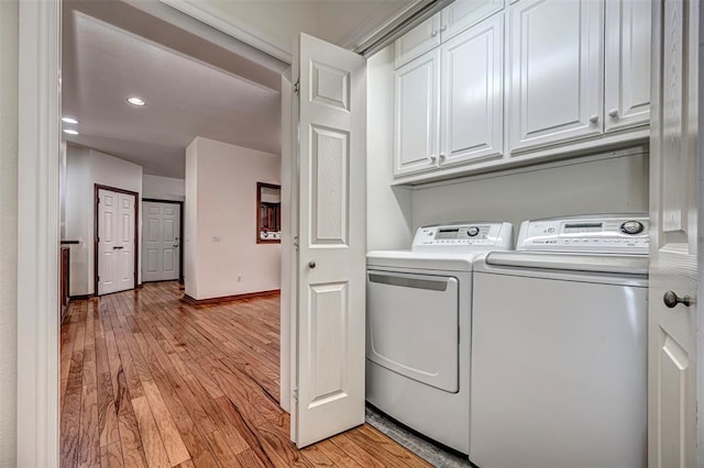 clothes washing area featuring cabinets, light wood-type flooring, and separate washer and dryer