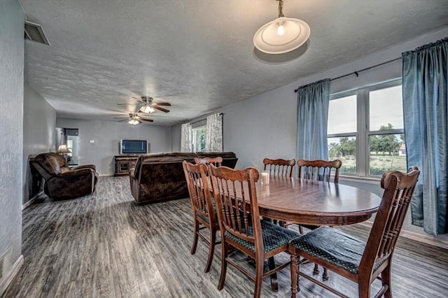 dining room with ceiling fan, wood-type flooring, and a textured ceiling