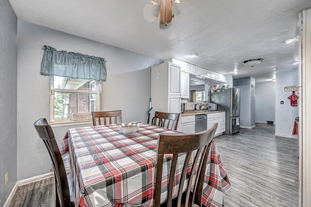 dining space with hardwood / wood-style floors, plenty of natural light, ceiling fan, and sink