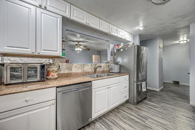 kitchen with white cabinets, sink, ceiling fan, appliances with stainless steel finishes, and light hardwood / wood-style floors