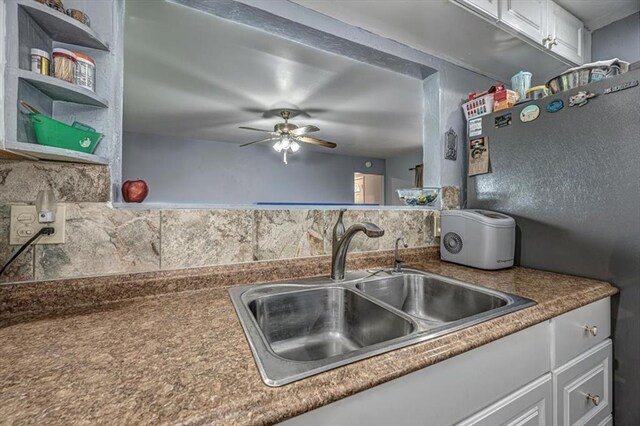 kitchen featuring backsplash, stainless steel fridge, white cabinetry, and sink