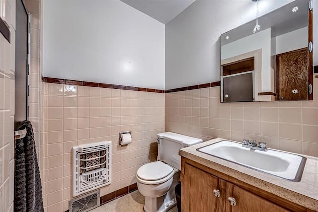 bathroom featuring vanity, heating unit, toilet, and tile walls