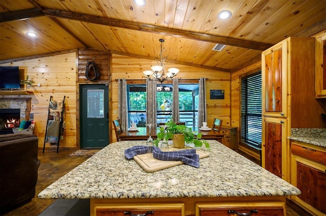 kitchen with pendant lighting, vaulted ceiling with beams, a kitchen island, and wood walls