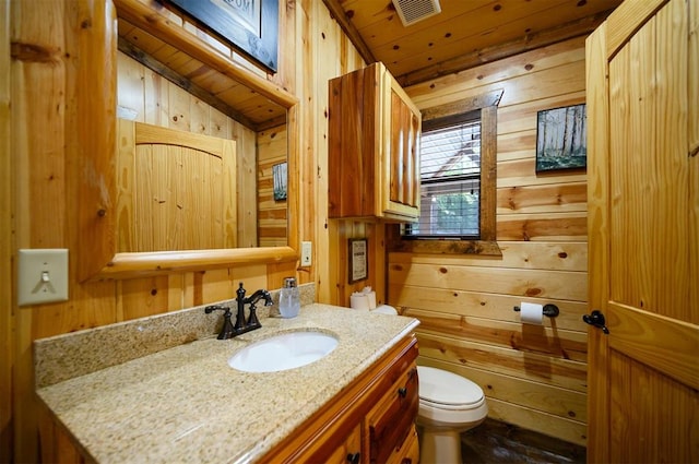 bathroom with wooden walls, vanity, lofted ceiling, and toilet