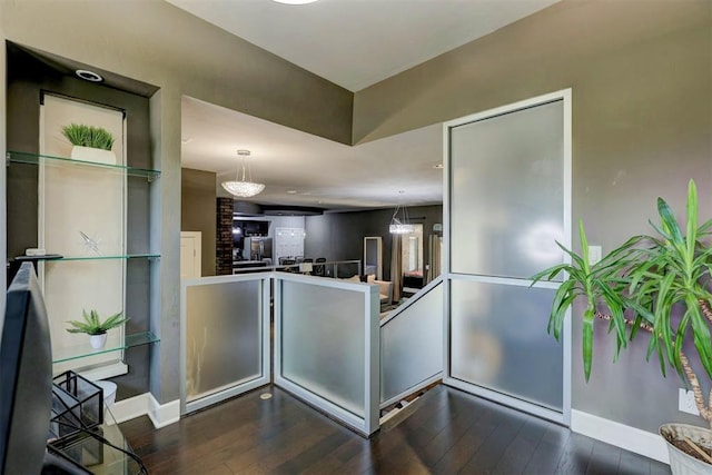 kitchen featuring pendant lighting, a notable chandelier, kitchen peninsula, and dark wood-type flooring