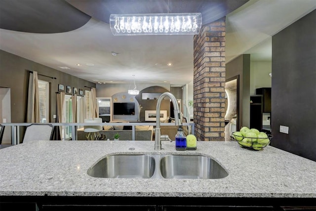 kitchen with light stone countertops, ornate columns, and sink