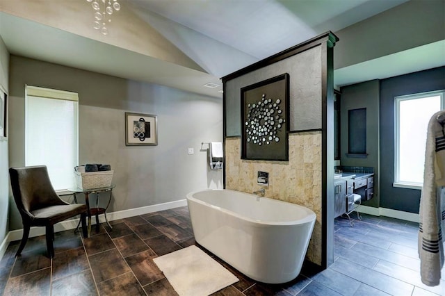 bathroom with a washtub, wood-type flooring, lofted ceiling, and vanity