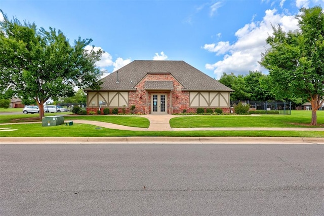 tudor-style house featuring french doors and a front lawn