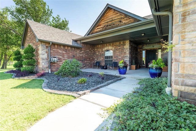 view of exterior entry featuring a yard and a patio area