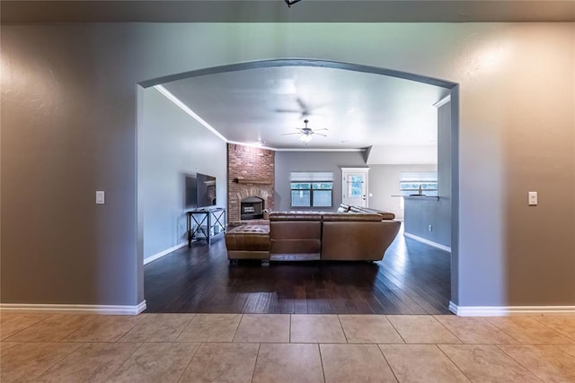 living room with ceiling fan, ornamental molding, a fireplace, and tile patterned flooring