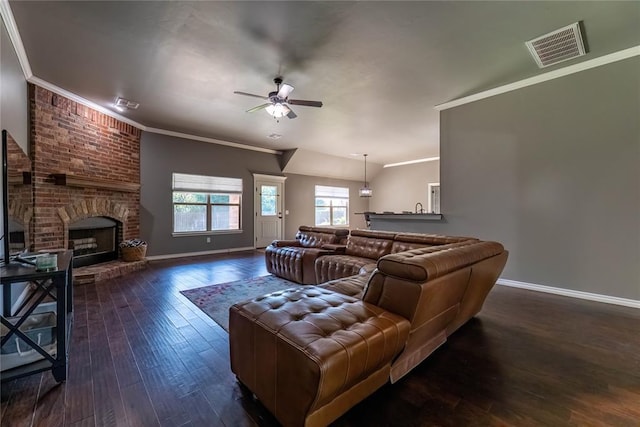 living room featuring ceiling fan, a fireplace, ornamental molding, and dark hardwood / wood-style floors