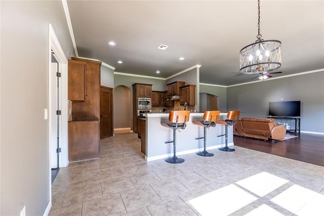 kitchen with light tile patterned flooring, stainless steel microwave, decorative light fixtures, a kitchen bar, and a notable chandelier