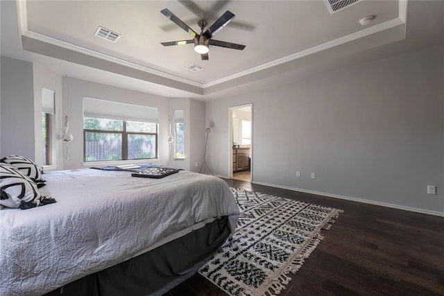 bedroom with ceiling fan, dark hardwood / wood-style floors, ensuite bathroom, a tray ceiling, and ornamental molding