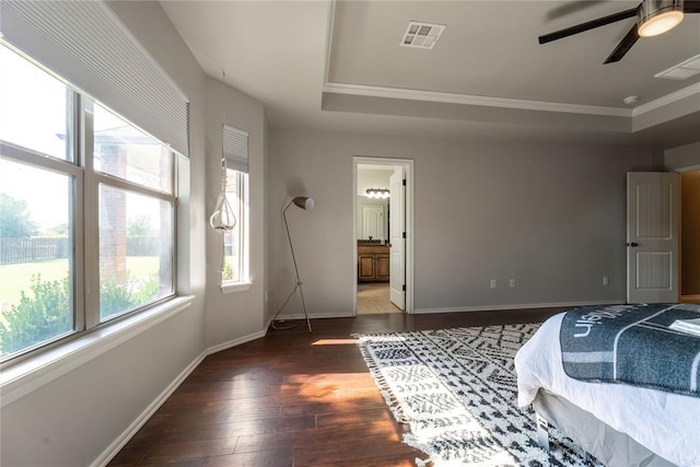 bedroom featuring connected bathroom, ornamental molding, dark hardwood / wood-style floors, a raised ceiling, and ceiling fan