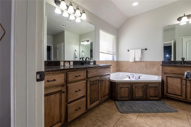 bathroom featuring tile patterned flooring, vanity, lofted ceiling, and a bath