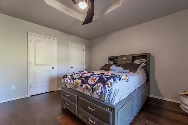 bedroom featuring a raised ceiling, ceiling fan, and dark hardwood / wood-style flooring