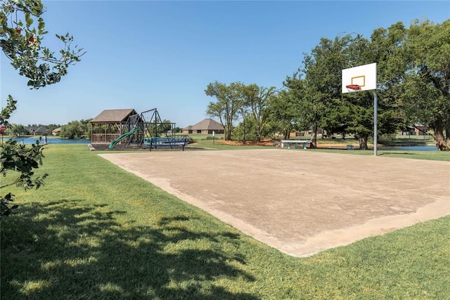 view of sport court featuring a water view, a playground, and a lawn