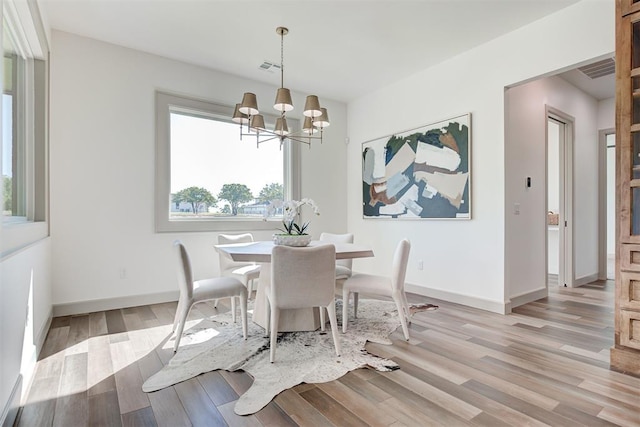 dining space with light hardwood / wood-style flooring and an inviting chandelier