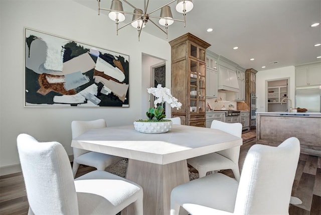 dining area with dark hardwood / wood-style flooring, a chandelier, and sink