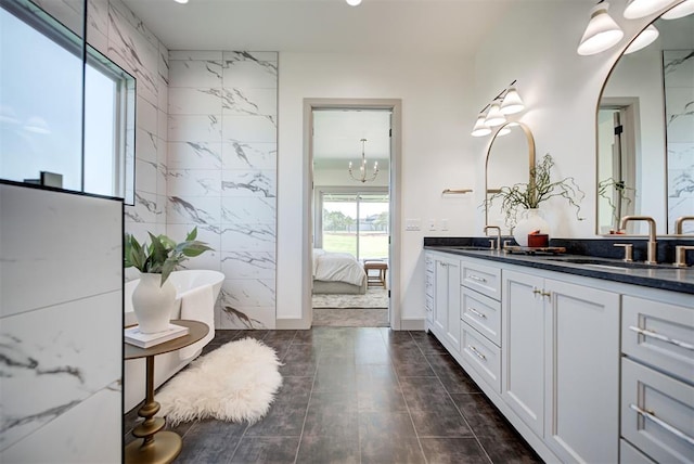 bathroom featuring a bathtub, vanity, tile walls, and a notable chandelier