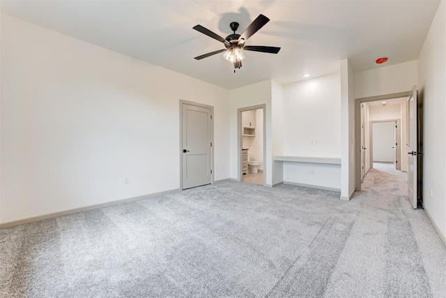 unfurnished bedroom with connected bathroom, ceiling fan, and light colored carpet